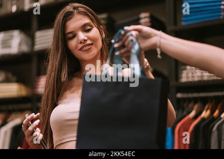 Ein süßes Mädchen, das dem Verkäufer die Einkaufstasche wegnimmt Stockfoto