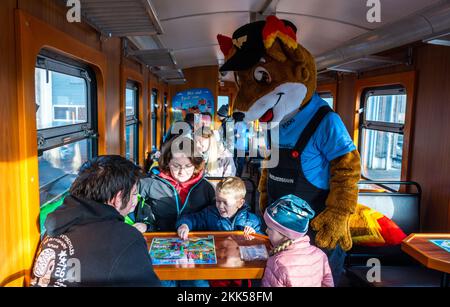 Oberwiesenthal, Deutschland. 25.. November 2022. Eine Familie testet das Spiel „Dampf ab!“ (Dampf auf!) Zusammen mit dem Maskottchen Feuerfuchs bei der Inbetriebnahme des neuen Wildwagens der Fichtelbergbahn. Es ist das erste Wildauto auf einer sächsischen Schmalspurbahn. Die sächsische Dampfeisenbahngesellschaft (SDG) investierte 11.500 Euro in die Umrüstung und Konstruktion des Autos. Kredit: Kristin Schmidt/dpa/Alamy Live News Stockfoto