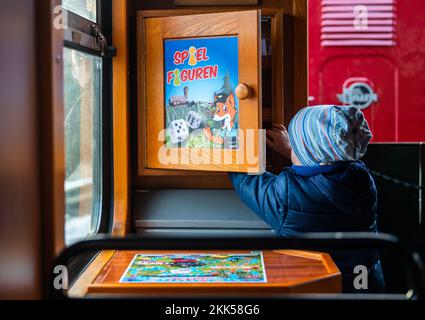 Oberwiesenthal, Deutschland. 25.. November 2022. Ein Kind nimmt bei der Einweihung des neuen Sportwagens der Fichtelbergbahn Spielteile aus einer Schachtel. Es ist das erste Wildauto auf einer sächsischen Schmalspurbahn. Die sächsische Dampfeisenbahngesellschaft (SDG) investierte 11.500 Euro in die Umrüstung und Gestaltung des Beförderungsmittels. Kredit: Kristin Schmidt/dpa/Alamy Live News Stockfoto