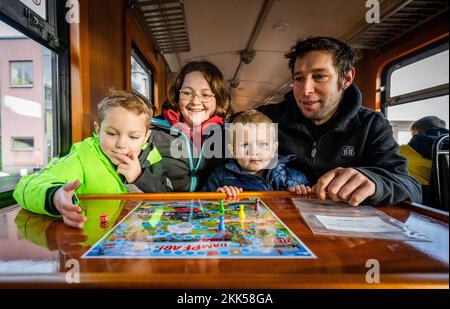 Oberwiesenthal, Deutschland. 25.. November 2022. Die Brüder Leon (6, l) und Jacob (4) spielen das Spiel „Dampf ab!“ Mit ihren Eltern Anja und Johannes frei während der Inbetriebnahme des neuen Sportwagens der Fichtelbergbahn. Es ist der erste Wildwaggon auf einer Schmalspurbahn in Sachsen. Die sächsische Dampfeisenbahngesellschaft (SDG) investierte 11.500 Euro in die Umrüstung und Konstruktion des Autos. Kredit: Kristin Schmidt/dpa/Alamy Live News Stockfoto