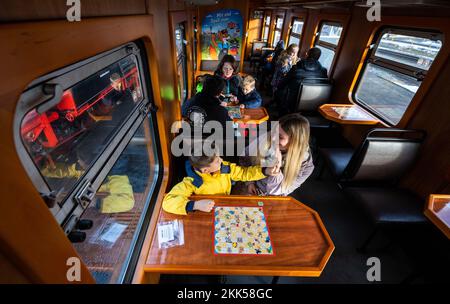 Oberwiesenthal, Deutschland. 25.. November 2022. Der sechsjährige Charly und seine Schwester Julia (vorne) spielen bei der Inbetriebnahme des neuen Spielwagens auf der Fichtelbergbahn gemeinsam Würfelspiele. Es ist der erste Wildwaggon auf einer Schmalspurbahn in Sachsen. Die sächsische Dampfeisenbahngesellschaft (SDG) investierte 11.500 Euro in die Umrüstung und Konstruktion des Autos. Kredit: Kristin Schmidt/dpa/Alamy Live News Stockfoto