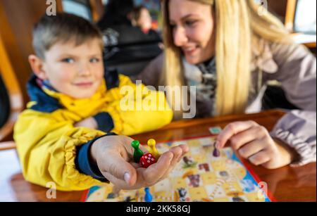 Oberwiesenthal, Deutschland. 25.. November 2022. Der sechsjährige Charly und seine Schwester Julia (vorne) spielen bei der Inbetriebnahme des neuen Spielwagens auf der Fichtelbergbahn gemeinsam Würfelspiele. Es ist der erste Wildwaggon auf einer Schmalspurbahn in Sachsen. Die sächsische Dampfeisenbahngesellschaft (SDG) investierte 11.500 Euro in die Umrüstung und Konstruktion des Autos. Kredit: Kristin Schmidt/dpa/Alamy Live News Stockfoto