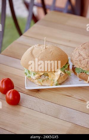 Gesundes veganes Abendessen - hausgemachte Burger mit vegetarischem Kotelett, eingelegter Gurke und Grünzeug im Freien. Stockfoto