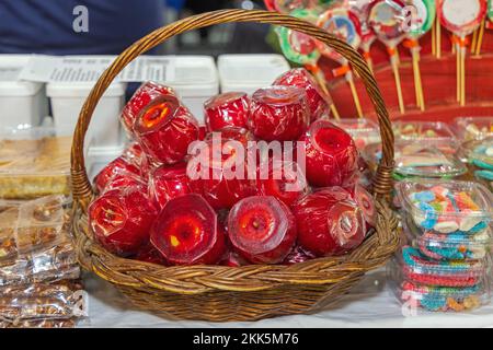 Ganze rote Süßigkeiten-Äpfel mit Zuckerbeschichtung im Korb beim Herbstfestival Stockfoto