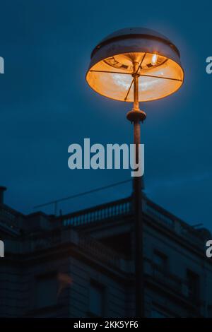 Eine vertikale Aufnahme einer Straßenbeleuchtung auf einer Straße, die nachts in Barcelona glüht Stockfoto