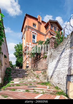 Fußweg mit roten Ziegeltreppen führt zu alten traditionellen Gebäuden und Bäumen, an einem sonnigen Tag, Balat Viertel, Istanbul, Türkei Stockfoto