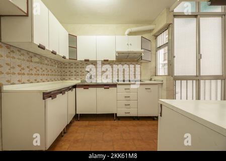 Küche mit alten weißen Möbeln, Trennwänden aus Aluminium mit durchsichtigem Glas und klassischen Fliesenwänden Stockfoto