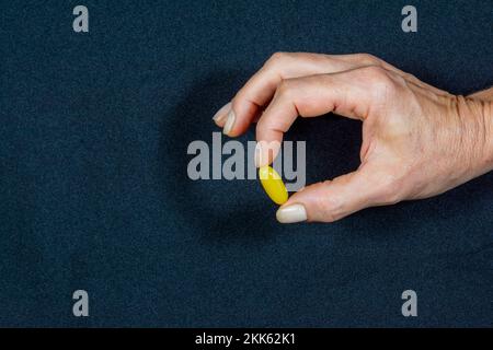 Eine Nahaufnahme einer Person, die ein Tablet in den Fingern auf schwarzem Hintergrund hält Stockfoto