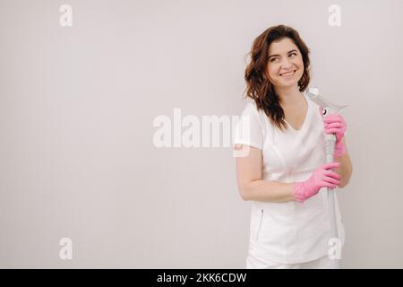 Porträt des Meisters der Laserhaarentfernung. Eine Frau in einem weißen Kittel hält ein Laser-Haarentfernungsgerät in den Händen Stockfoto