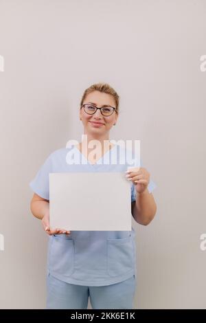 Porträt einer Ärztin im blauen Gewand mit weißem, leerem Blatt Stockfoto