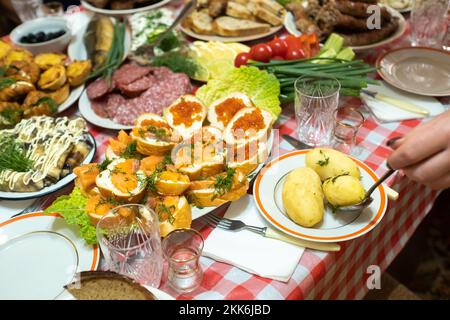 Auf dem Banketttisch gab es viele verschiedene Speisen und es gab gekochte Kartoffeln mit Dill. Eine große Anzahl an fertig zubereiteten Gerichten auf dem Tisch. Urlaub im Stockfoto