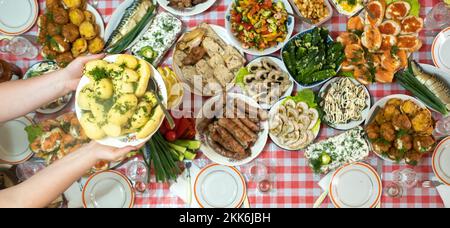 Auf dem Banketttisch gab es viele verschiedene Speisen und es gab gekochte Kartoffeln mit Dill. Eine große Anzahl an fertig zubereiteten Gerichten auf dem Tisch. Urlaub im Stockfoto