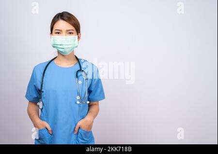 Ein Porträt einer jungen asiatischen Krankenschwester, die eine Operationsmaske auf weißem Hintergrund trägt Stockfoto