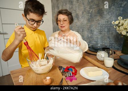 Der Junge kocht köstliches Essen mit seiner Großmutter Stockfoto