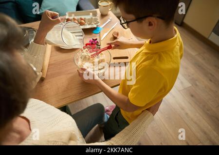 Der Junge kocht köstliches Essen mit seiner Oma Stockfoto