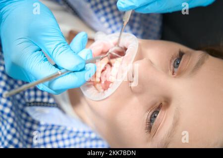 Zahnarzt führt professionelle Reinigung von Knabenzähnen in Schutzhandschuhen durch Stockfoto