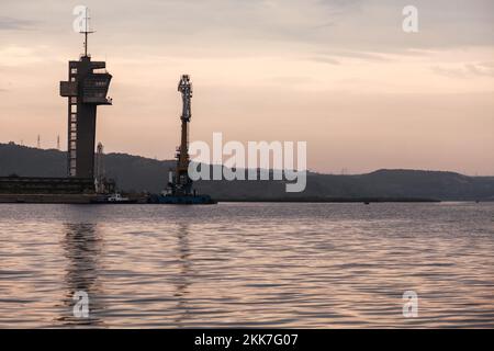 Küstenlandschaft mit Seeverkehrskontrollturm und schwimmendem Kran am Abend. Hafen von Varna, Bulgarien. Stockfoto