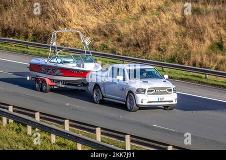 2018 American White Dodge RAM Pick-up Crew Cab, mit 5,7-Liter Hemi V8-Motor. Abschleppen des Motorboots Master Craft M40 X-Serie; Fahrt auf der Autobahn M6, Großbritannien Stockfoto