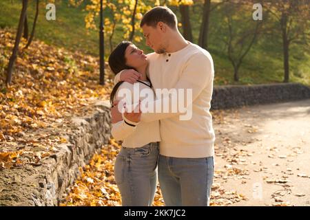 Ein Paar in leichten Pullover steht, umarmt, inmitten der Herbstlandschaft Stockfoto