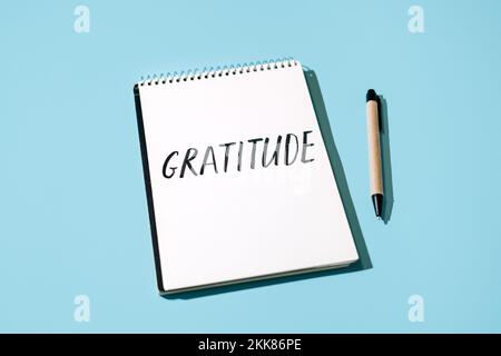 Wie man Dankbarkeit übt. Wort Dankbarkeit in offenem Notizbuch auf Tisch. Gute Dinge zu bemerken, gute Dinge zu schätzen. Drücken Sie sich selbst Dankbarkeit aus. - Ja, Richtig Stockfoto