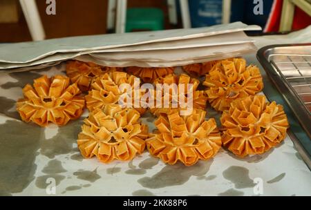 Reihen frisch gebratener, blumiger, traditioneller thailändischer Dessert namens Kanom Dokchok zum Verkauf an einem lokalen Verkaufsstand Stockfoto