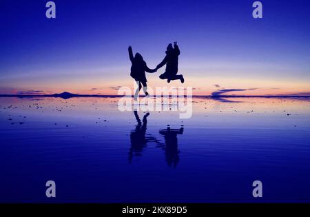 Popkunst-Stil, königlich und korallenrosa, mit fröhlicher Silhouette auf dem SPIEGELEFFEKT der Uyuni Salzebenen in Bolivien, Südamerika Stockfoto