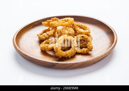 Ein isolierter Schuss knuspriger Zwiebelringe auf einer Holzplatte auf weißem Hintergrund Stockfoto