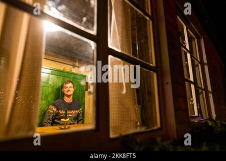 Breitnau, Deutschland. 25.. November 2022. Jonas Eckert, Veranstalter des Weihnachtsmarkts in Ravennaschlucht, sitzt in einem mobilen „Stubede“, dem traditionellen (und eigentlich nicht mobilen) Food Point alter Schwarzwaldfarmen auf dem Weihnachtsmarkt. Nachdem der Weihnachtsmarkt in der Ravennaschlucht aufgrund der Corona-Pandemie im Jahr 2020 eingestellt werden musste und im folgenden Winter 2021 nur für wenige Tage geöffnet werden konnte, Dieses Jahr dürfen Besucher an allen vier Adventswochenenden den Weihnachtsmarkt unter dem Viadukt der Höllentalbahn besuchen. Kredit: Philipp von Ditfurth/dpa/Alamy Live News Stockfoto