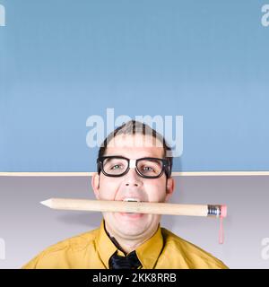 Geeky Geschäftsmann hält massive Bleistift im Mund vor der Tafel zu lernen, bei der Ausarbeitung eines Big Business-Plans Stockfoto