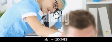 Frau Dermatologe untersuchen männlichen Patienten Körper, überprüfen Sie die Haut auf dem Rücken mit Lupe Stockfoto