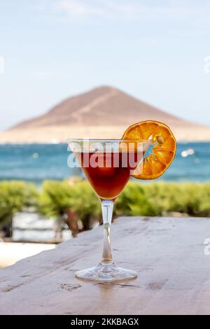 Ein vertikales Nahtbild eines Blut-Sand-Cocktails, Mixgetränks in einem Glas, dekoriert mit einer Zitronenscheibe Stockfoto