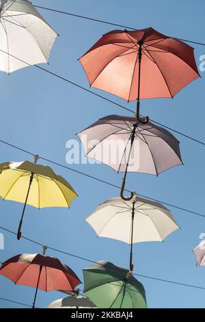 Straßenlandschaft aus mehrfarbigen Regenschirmen über dem Boden aufgehängt, um die Stadt unter blauem Himmel zu schmücken Stockfoto