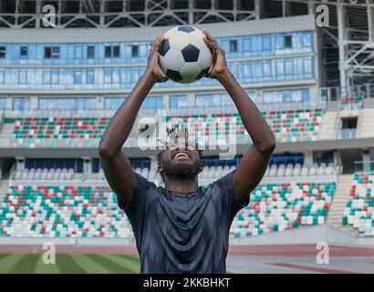 ein afroamerikanischer Fußballspieler, der den Ball im Stadion in den Händen hält Stockfoto