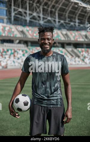 Ein junger Mann steht in einem Stadion mit einem Fußball in der Hand Stockfoto