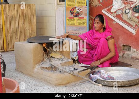 Eine Nahaufnahme einer Frau, die Chapatti-Brot auf einem offenen Feuer backt Stockfoto