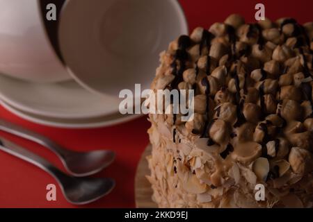 Fotografieren Sie Walnusskuchen und weiße Gerichte auf rotem Hintergrund Stockfoto