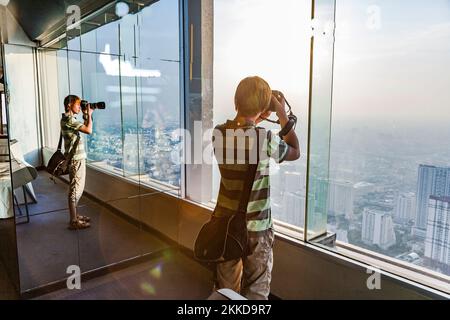 Bangkok, Thailand - 2. Januar 2010: Menschen genießen es, die Skyline von Bangkok von der Plattform am Aussichtspunkt Mahanakhon Skywalk aus zu betrachten. Stockfoto