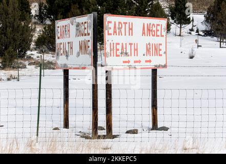 Boulder, Montana, USA. 25.. November 2022. Wetterbekloppte Schilder für die Earth Angel Health Mine, eine von einer Handvoll „Gesundheitsminen“ in Montana, die vorgeben, Krankheiten mit dem Radongas zu heilen, das aus den Wänden dieser veralteten Uranminen sickert. Radon ist ein tödliches Gas, wenn es in ausreichenden Mengen eingeatmet wird; einige Befürworter der „natürlichen Heilung“ und der Theorie der Strahlungshormesis, darunter viele in den Amischen und Mennoniten, glauben jedoch entgegen der Überlegenheit wissenschaftlicher Beweise, dass kleinere Dosen von Radon Krankheiten heilen können. Die Minen sind wegen des wi geschlossen Stockfoto