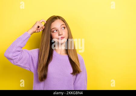 Foto von einer träumigen, intelligenten Schulmädchen Teenager tragen warmen Strickpullover Kratzkopf Look leerer Raum Produkt isoliert auf gelber Farbe Stockfoto