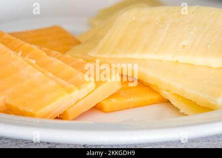 Eine Nahaufnahme zweier Arten von Käsescheiben auf einem weißen Teller Stockfoto