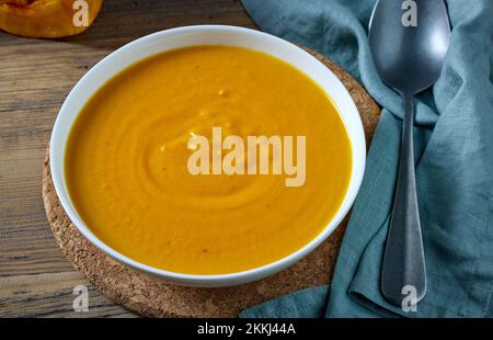 Schüssel mit Kürbiscremesuppe auf dem Küchentisch Stockfoto