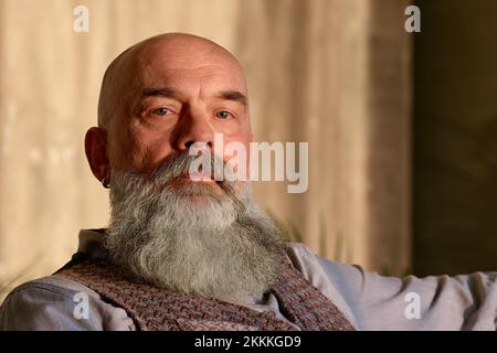 Reifer bärtiger Mann, der auf einem Stuhl sitzt. Stockfoto