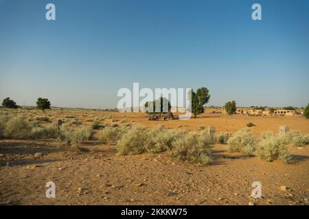 Ranautar, ein abgelegenes Wüstendorf in der Wüste. Entfernter Horizont, heißer Sommer mit wolkenlosem blauem Hintergrund, Thar Desert, Rajasthan, Indien Stockfoto