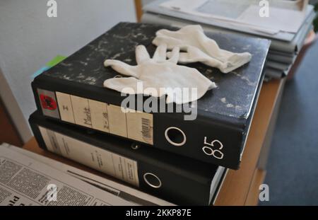 PRODUKTION – 24. November 2022, Mecklenburg-Vorpommern, Güstrow: Handschuhe liegen auf Aktenordnern im Gemeindearchiv Güstrow. Die Archive in Mecklenburg-Vorpommern sehen sich aufgrund des Ablaufs der Aufbewahrungsfristen in der Verwaltung einer Menge Arbeit in Form von neuem Material gegenüber. (Dpa „Welle neuer Dokumente rollt zu Archiven im Nordosten“) Foto: Danny Gohlke/dpa Stockfoto