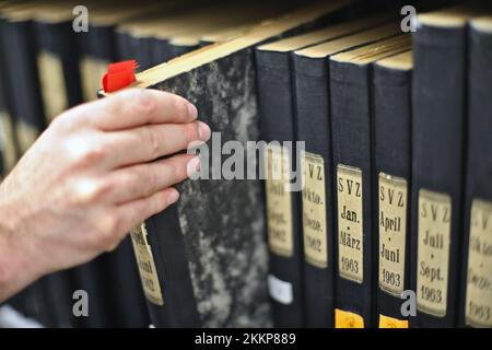 PRODUKTION – 24. November 2022, Mecklenburg-Vorpommern, Güstrow: Ein Mitarbeiter des Gemeindearchivs Güstrow holt einen Ordner mit alten Zeitungen aus einem Aktenschrank. Die Archive in Mecklenburg-Vorpommern sehen sich aufgrund des Ablaufs der Aufbewahrungsfristen in der Verwaltung einer Menge Arbeit in Form von neuem Material gegenüber. (Zu dpa „Welle neuer Dokumente rollt zu Archiven im Nordosten“) Foto: Danny Gohlke/dpa Stockfoto