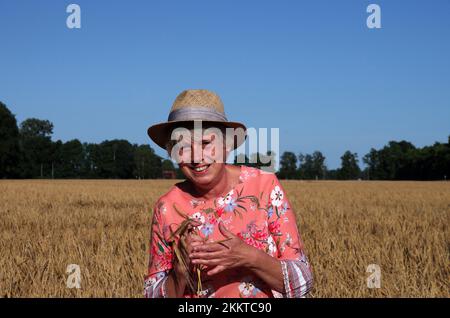 Porträt, Frau, Weibchen, draußen, eine Frau mit Strohhut steht in einem Getreidefeld Stockfoto