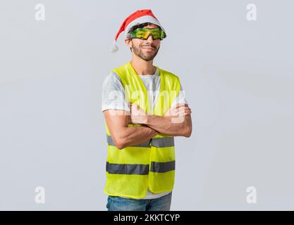 Porträt eines lächelnden Ingenieurs in einem weihnachtsmütze, Porträt eines Ingenieurs in einer Weste und einem weihnachtsmütze. Porträt eines fröhlichen Ingenieurs in Weste und Kan Stockfoto