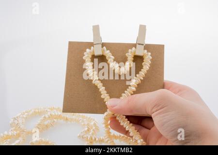 Perlenkette Formen Herz Form auf Papier auf weißem Hintergrund Stockfoto