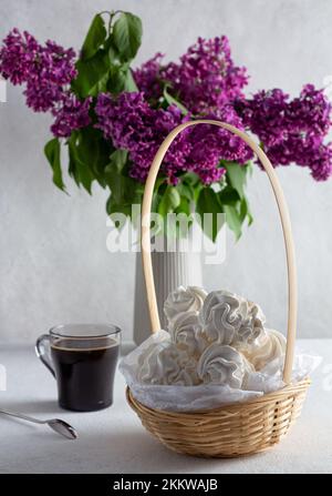 apfelzepfyr auf hellem Hintergrund auf einem Teller, im Hintergrund - eine Tasse Kaffee, Fliederzweige. Stockfoto