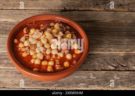 Tonschale mit Tripe und Kichererbsen auf einem alten Holzhintergrund. Stockfoto